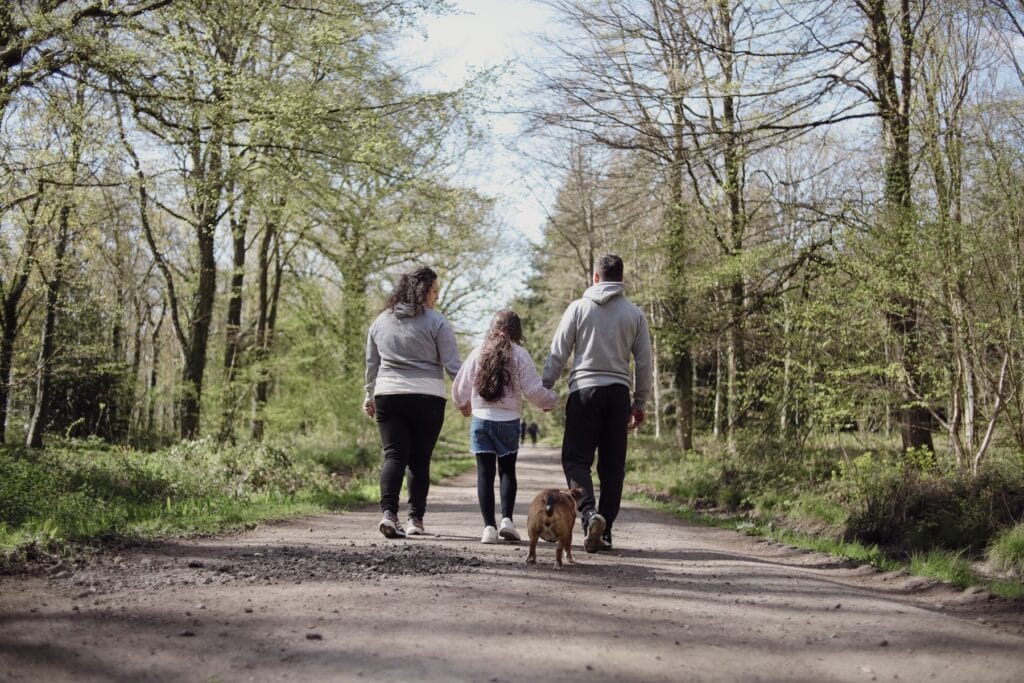 Familie går med hund på en sti i skoven