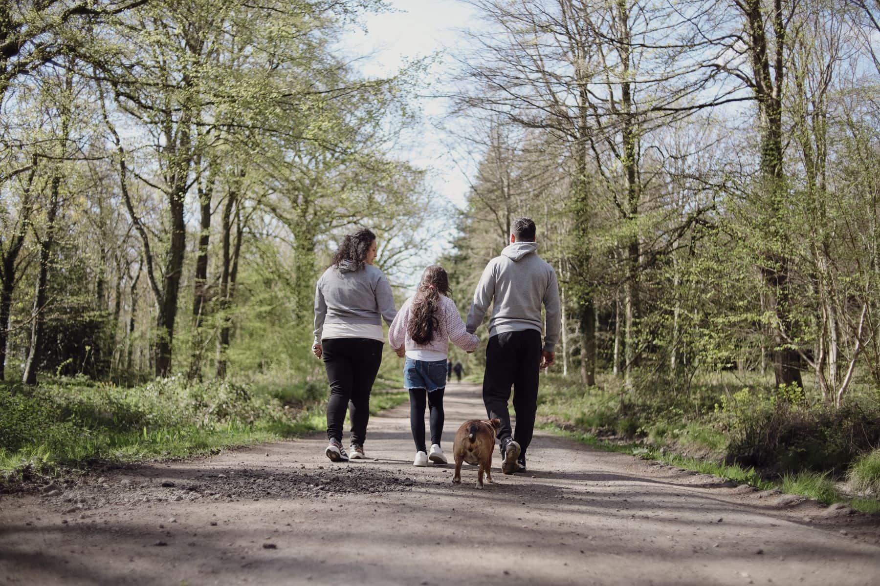 Familie går med hund på en sti i skoven